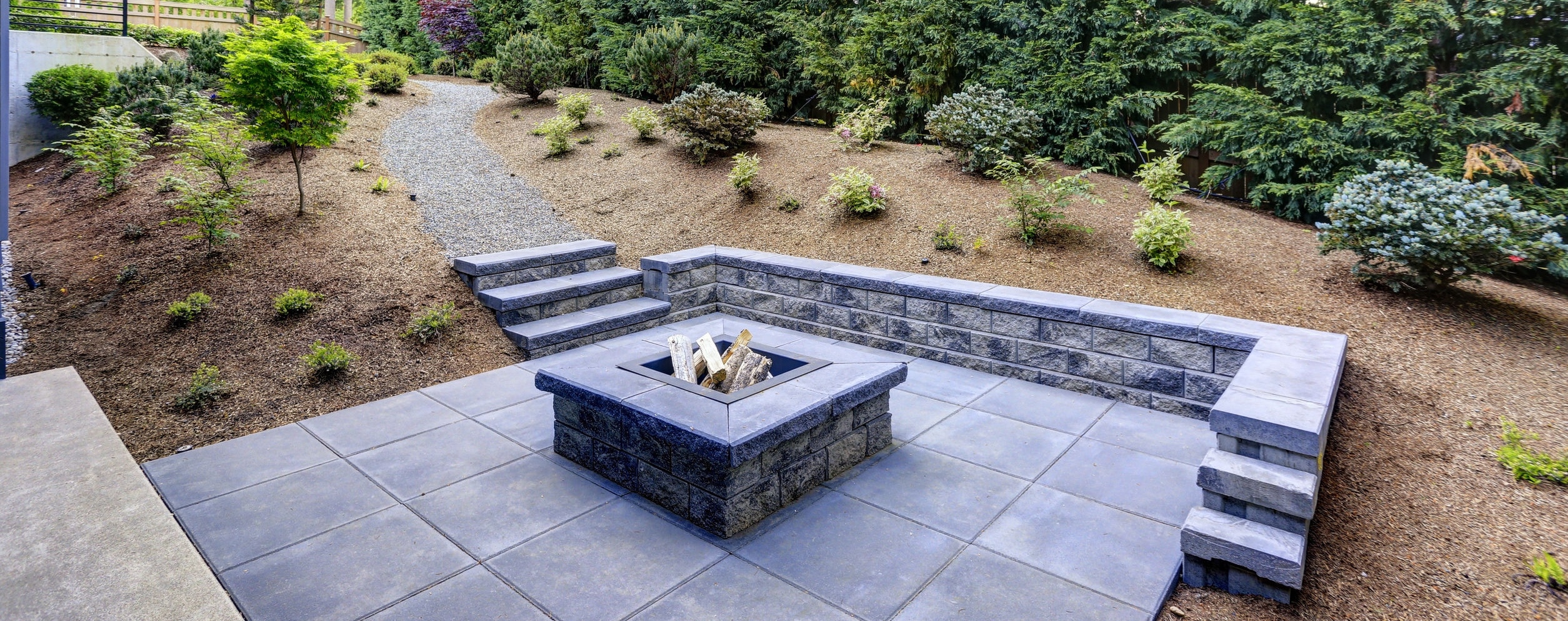 rectangular concrete fire pit framed by slate pavers and overlooking the lush garden