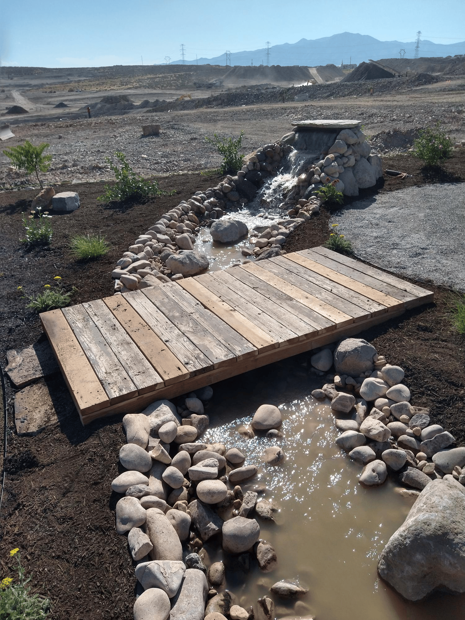 image Water feature including waterfall and river going under wooden walkway