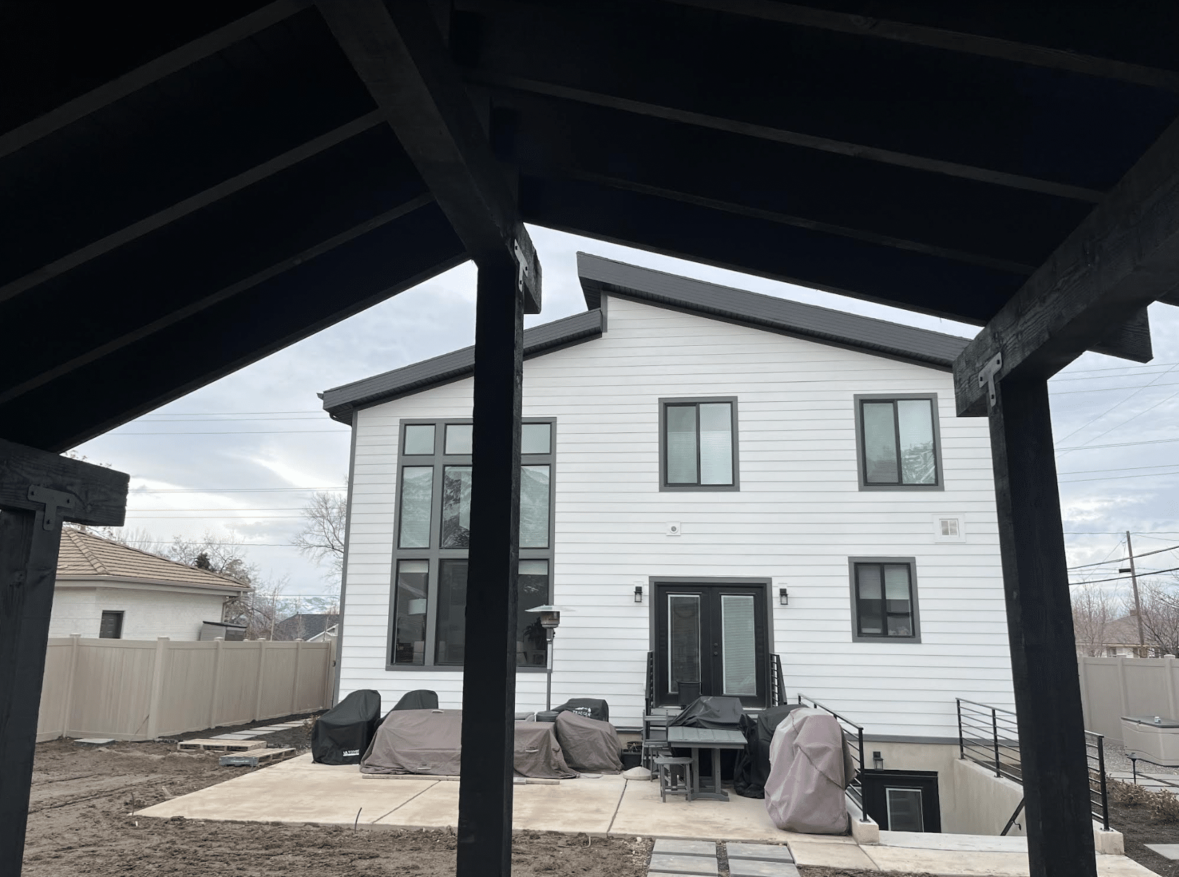 Screen Shot 2024-02-19 at 11.40.19 AM A white home as seen from under a new pergola built for a home.