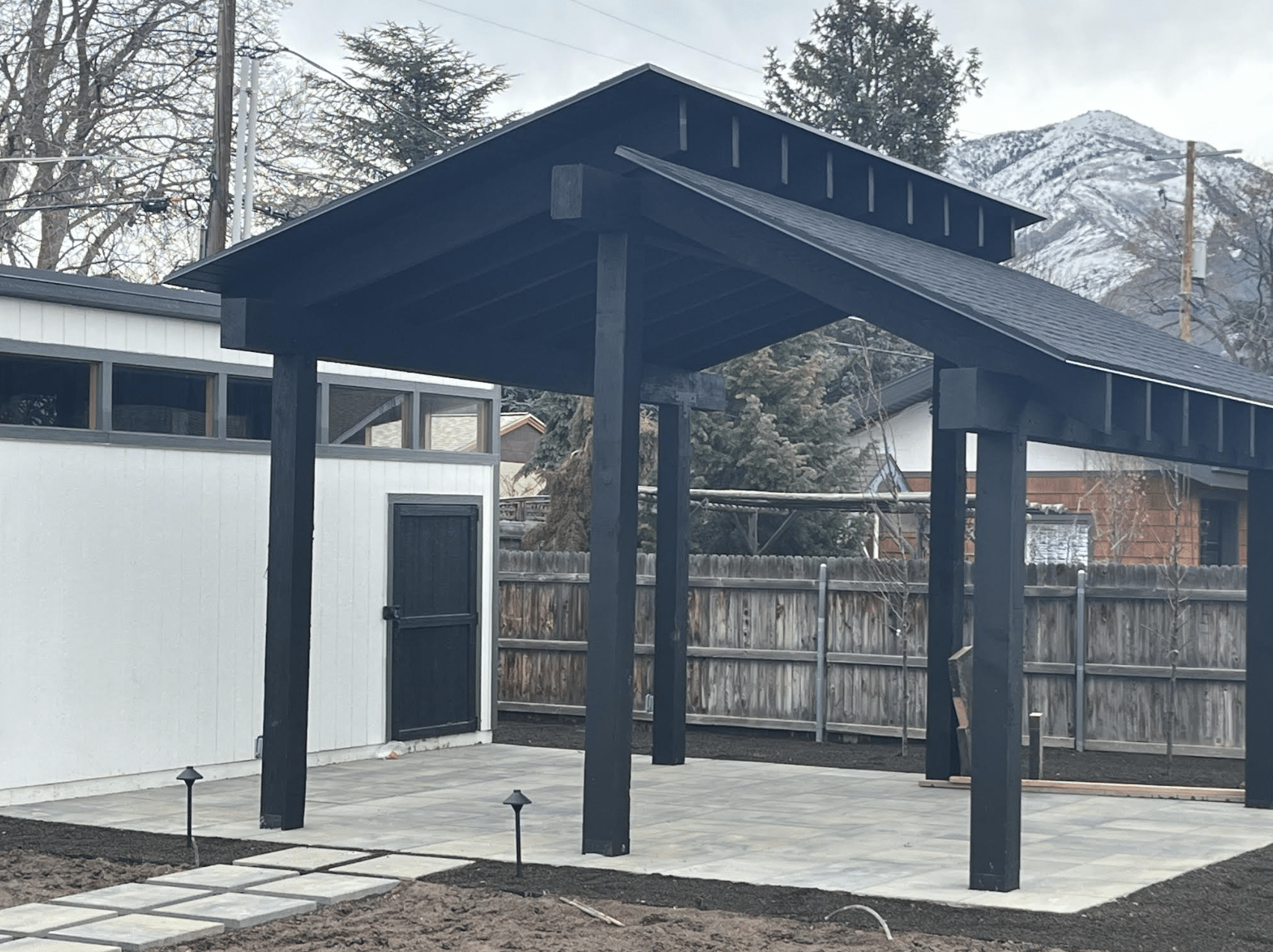 Screen Shot 2024-02-19 at 11.40.35 AM Black pergola built on a concrete patio for a home.