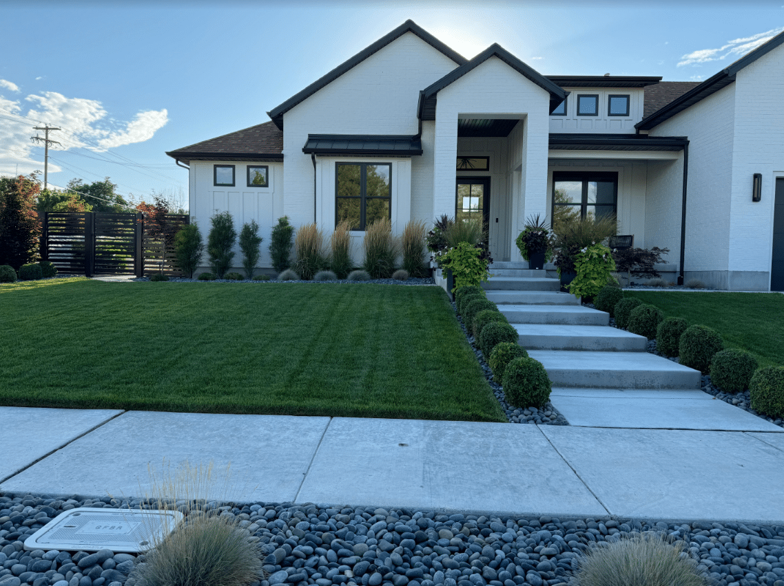 Screen Shot 2024-08-21 at 2.07.56 PM Large white house with new landscaping installed by Huskie'z Landscaping.