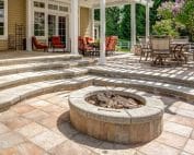 Backyard landscape with paver patio, stairs, fire pit, trees and turf