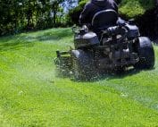 Landscaper on a riding lawn mower cutting grass